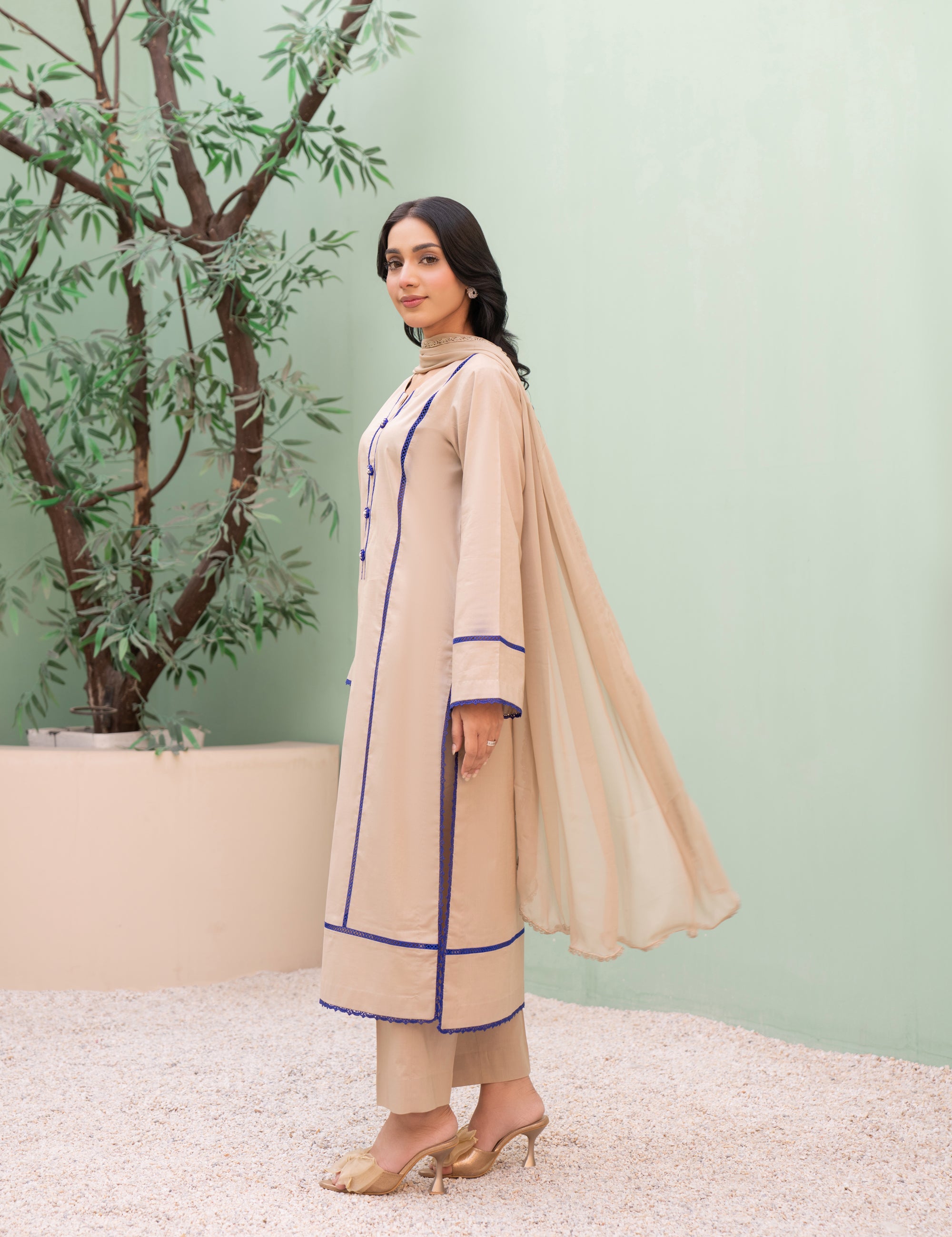 Woman in a beige traditional outfit with a light green background